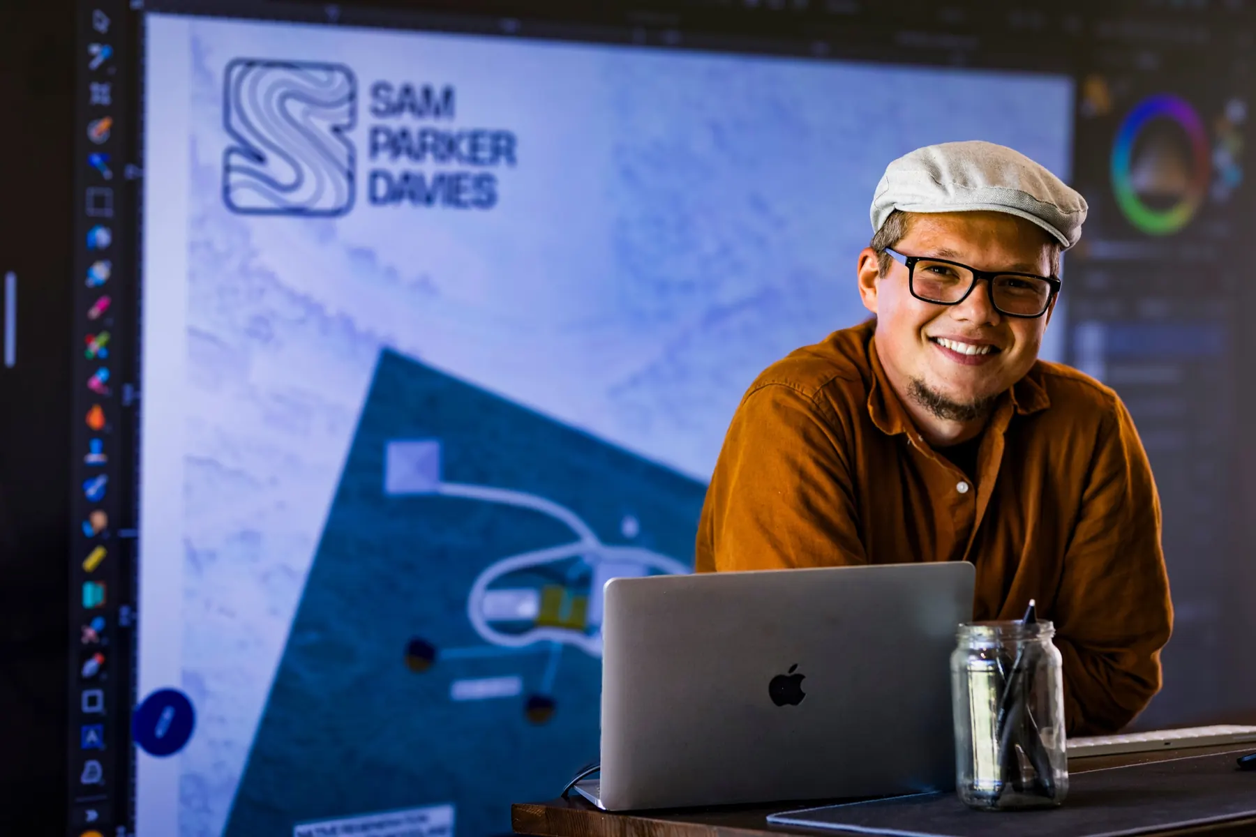 Sam smiling at a laptop in front of a site design